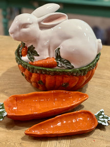 Bote con tapa en forma de conejo sobre zanahorias