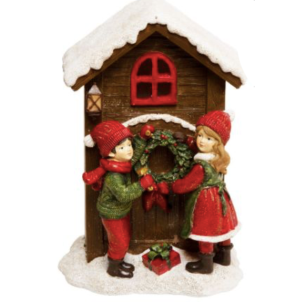 Figura decorativa navideña de niños colgando una corona en casa de invierno